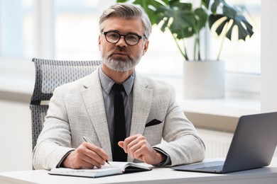 Photo of Banker taking notes at desk in office