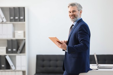 Banker with tablet near desk in office, space for text