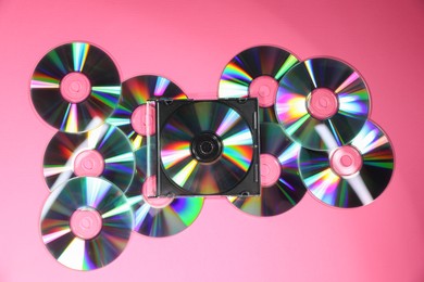 Photo of Many shiny compact discs on pink background, flat lay