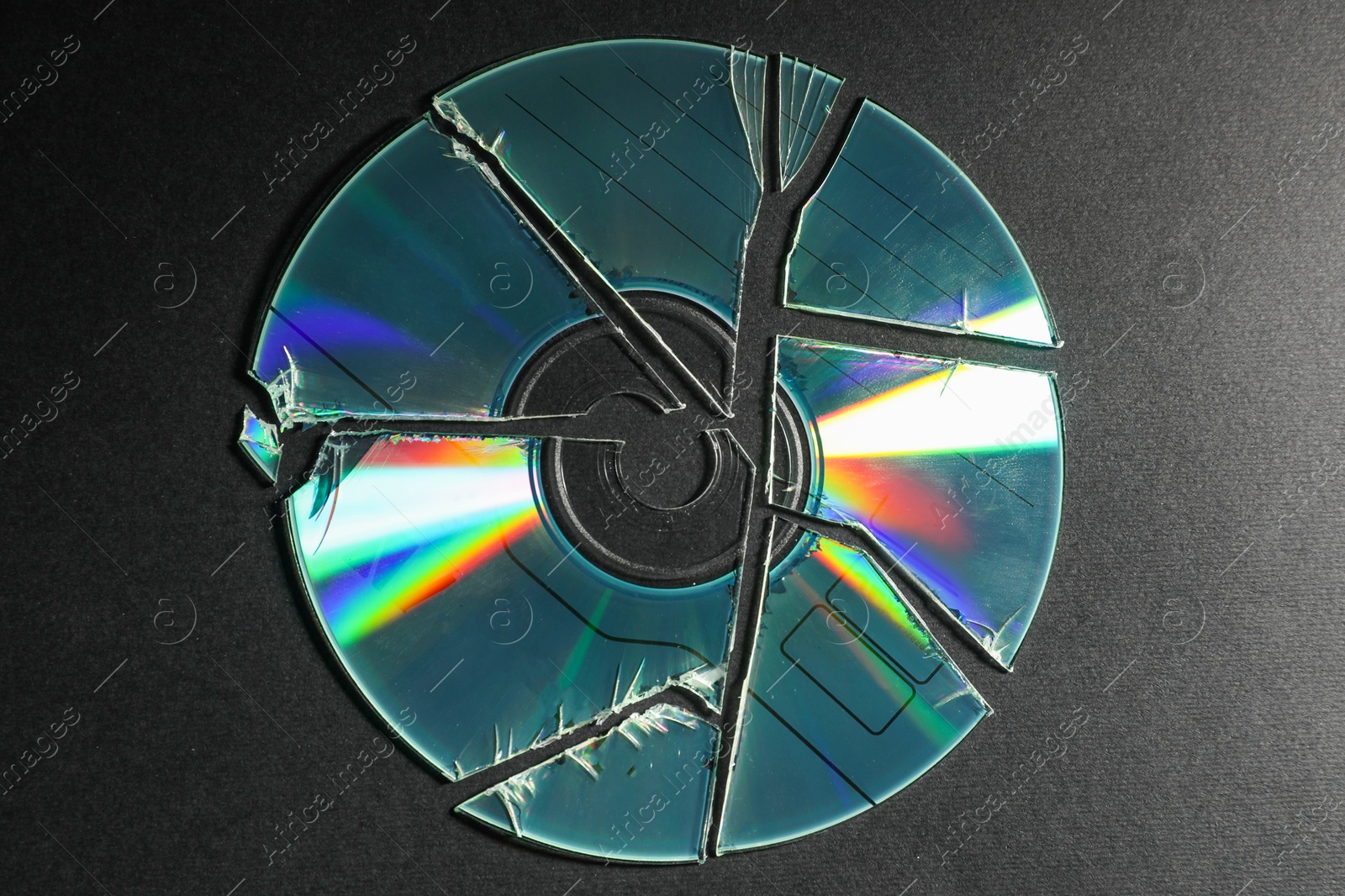 Photo of Broken compact disc on black background, top view