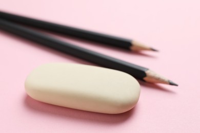 Photo of Eraser and pencils on pink background, closeup