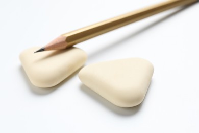 Photo of Erasers and pencil on white background, closeup