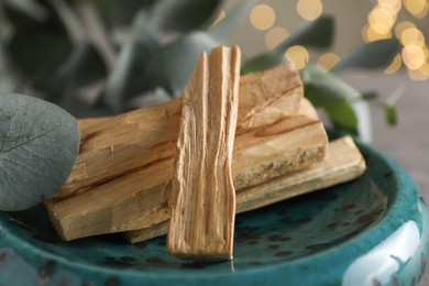 Photo of Palo santo sticks and eucalyptus leaves on table, closeup