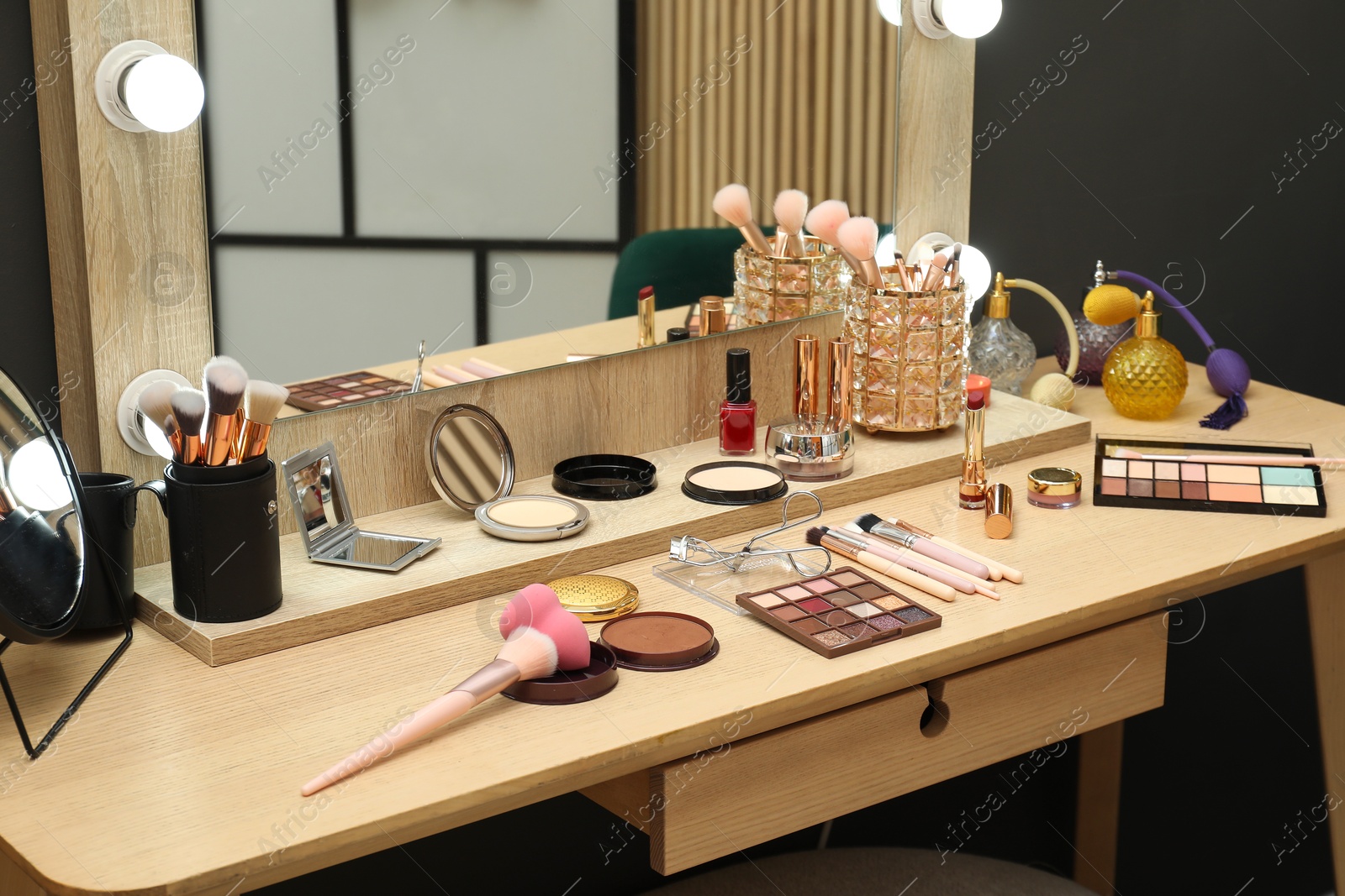 Photo of Makeup room. Mirror and cosmetic products on wooden dressing table indoors