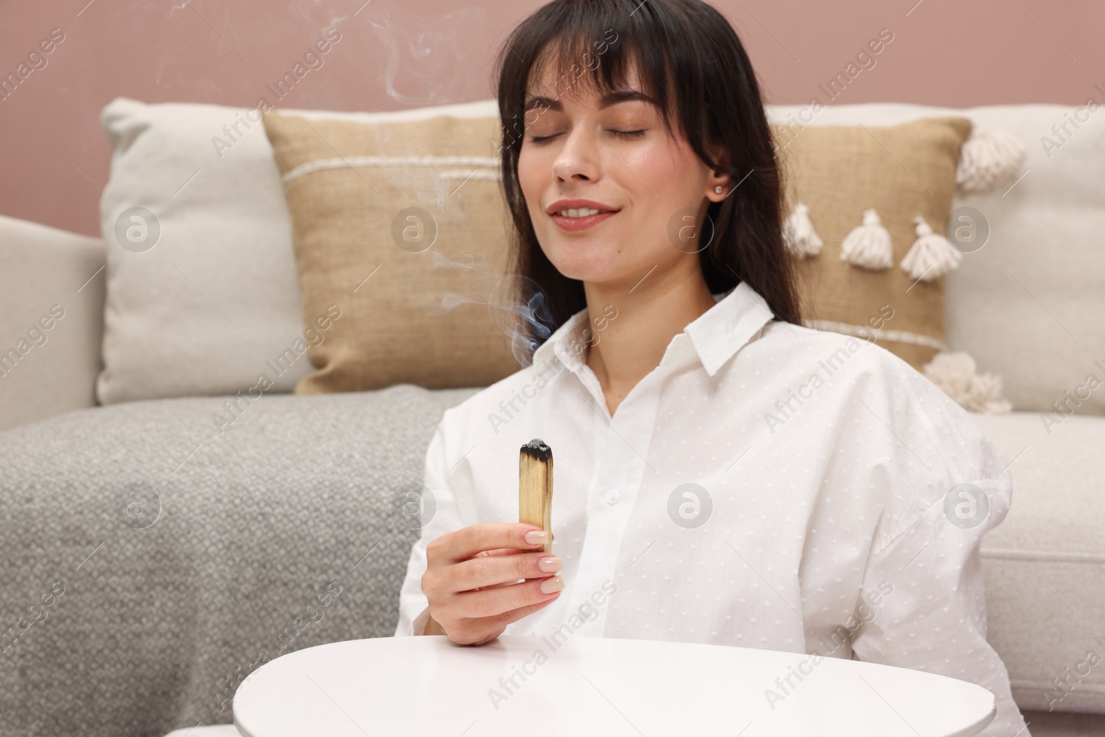 Photo of Woman with smoldering palo santo stick at home