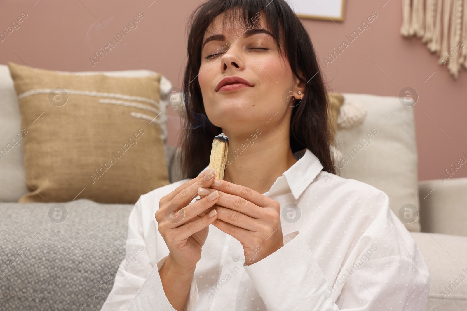 Photo of Woman with smoldering palo santo stick at home