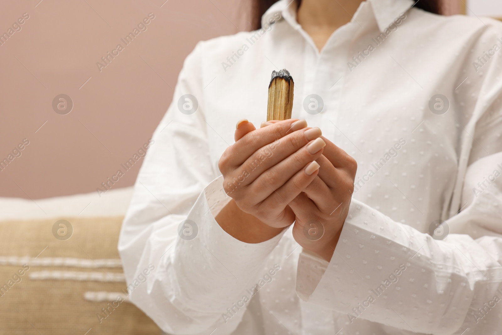 Photo of Woman with smoldering palo santo stick at home, closeup