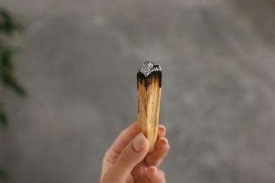 Photo of Woman with burnt palo santo stick indoors, closeup