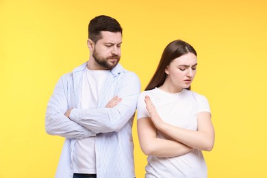 Photo of Resentful couple with crossed arms on yellow background