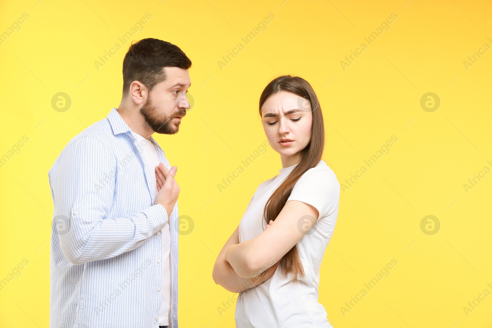 Photo of Angry couple arguing on yellow background. Relationship problem