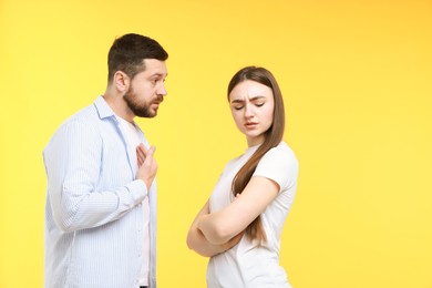 Photo of Angry couple arguing on yellow background. Relationship problem