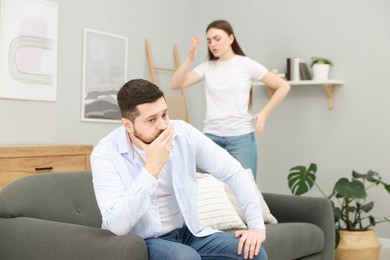 Photo of Resentful couple arguing at home, selective focus