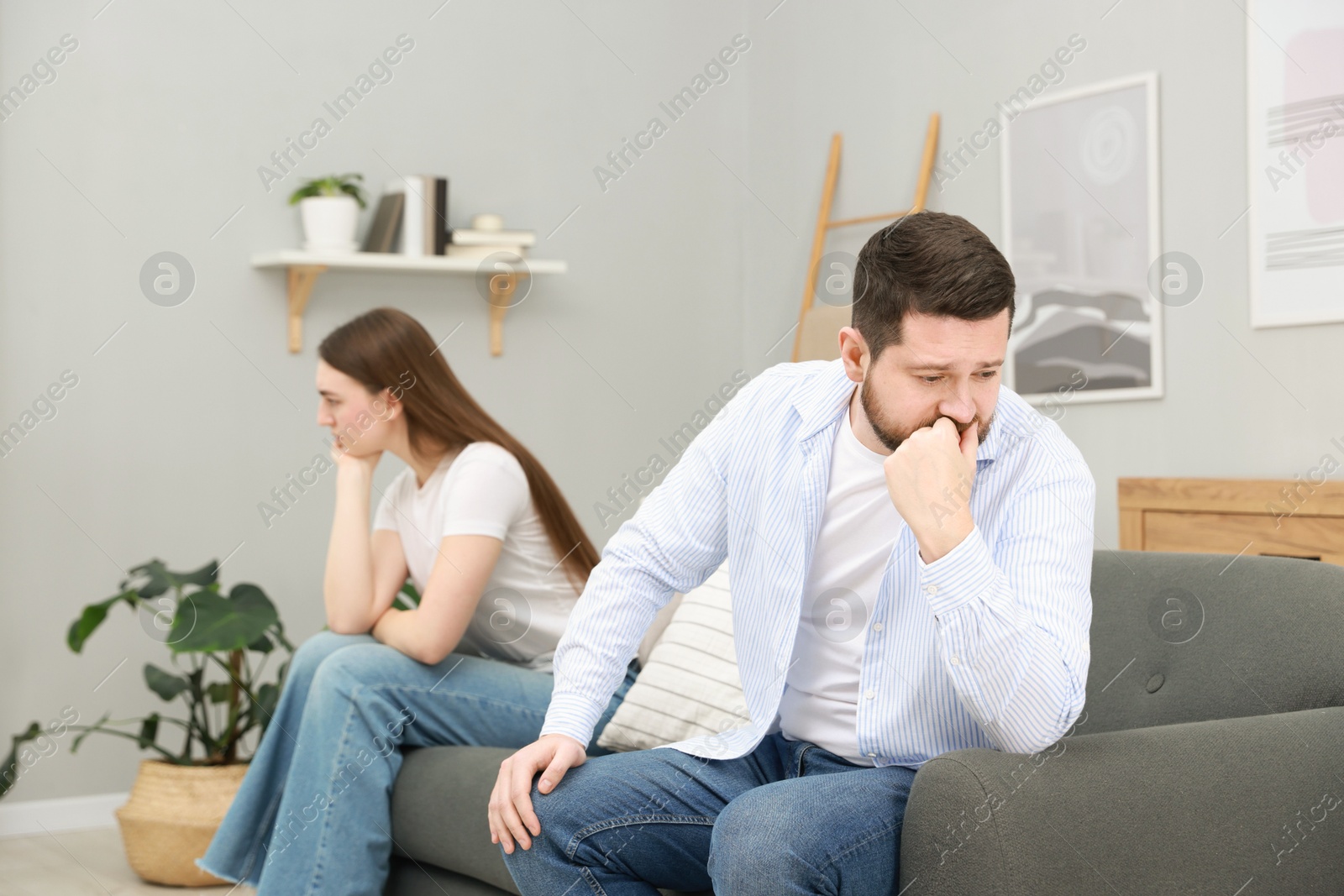 Photo of Resentful couple sitting on couch at home, selective focus