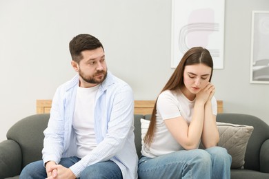 Photo of Resentful couple sitting on couch at home