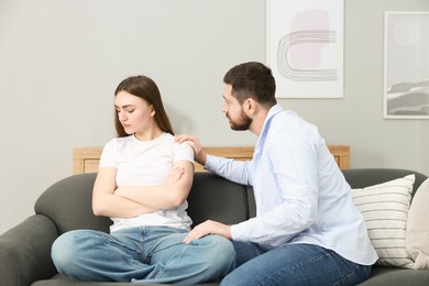 Photo of Man comforting his resentful girlfriend on couch at home