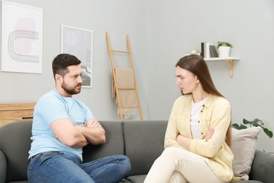 Photo of Resentful couple with crossed arms on couch at home