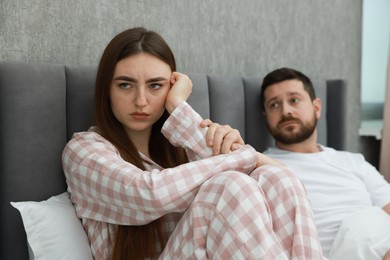 Photo of Man comforting his resentful girlfriend on bed at home, selective focus