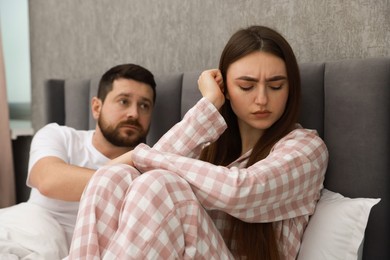 Photo of Man comforting his resentful girlfriend on bed at home, selective focus