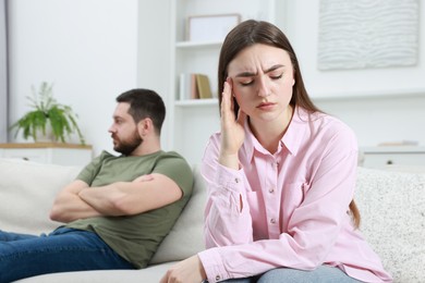 Resentful couple sitting on couch at home, selective focus