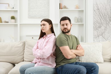 Photo of Resentful couple with crossed arms sitting on couch at home