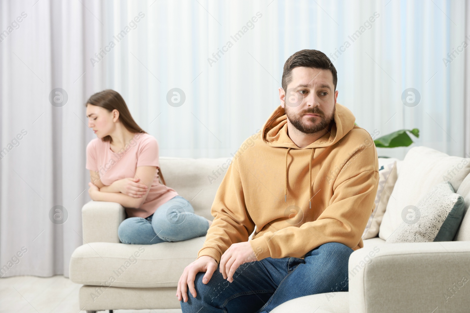 Photo of Resentful couple sitting on couch at home, selective focus