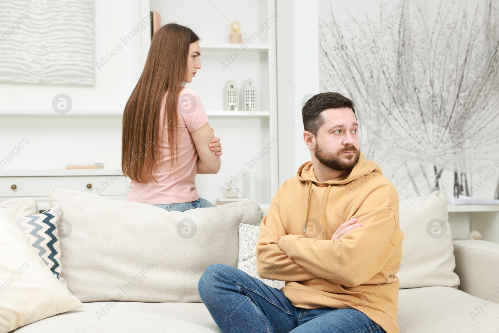 Photo of Resentful couple with crossed arms sitting on couch at home