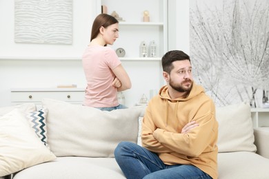 Photo of Resentful couple with crossed arms sitting on couch at home