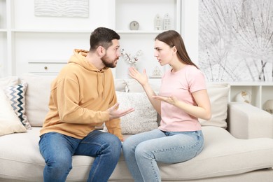 Photo of Angry couple arguing on couch at home