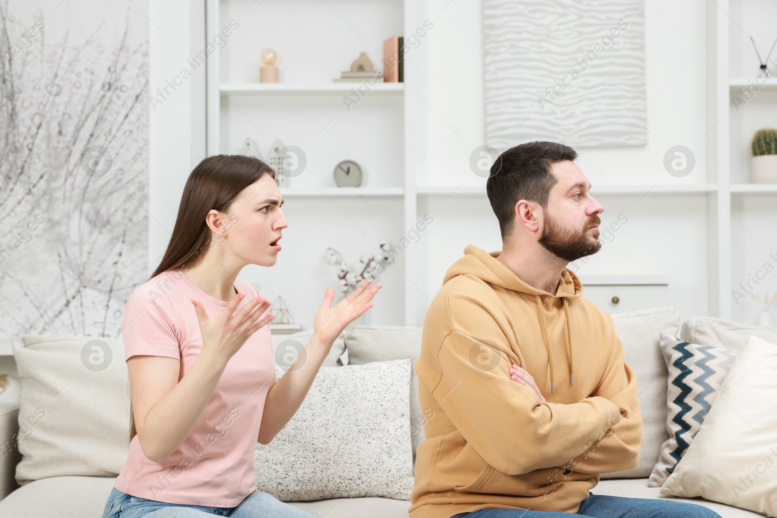 Photo of Angry couple arguing on couch at home