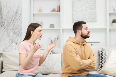 Photo of Angry couple arguing on couch at home