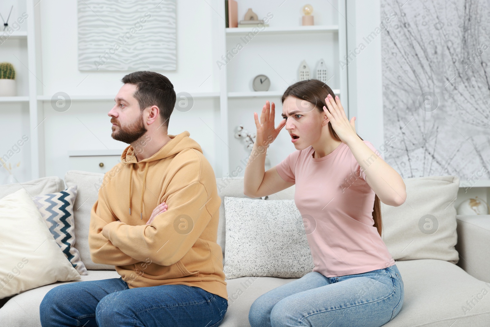 Photo of Angry couple arguing on couch at home