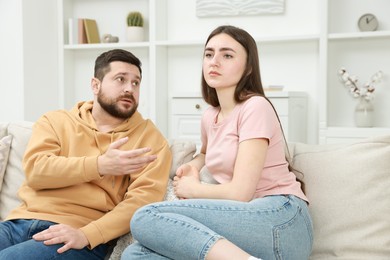 Photo of Angry couple arguing on couch at home