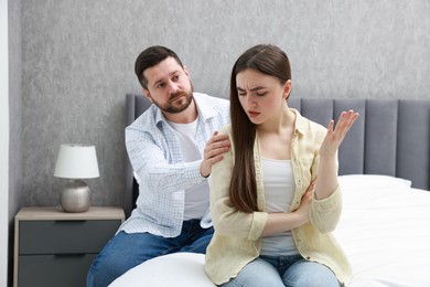 Photo of Man comforting his resentful girlfriend on bed at home