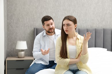 Photo of Angry couple arguing on bed at home