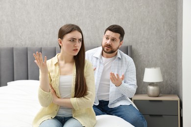 Photo of Angry couple arguing on bed at home