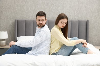 Resentful couple sitting on bed at home