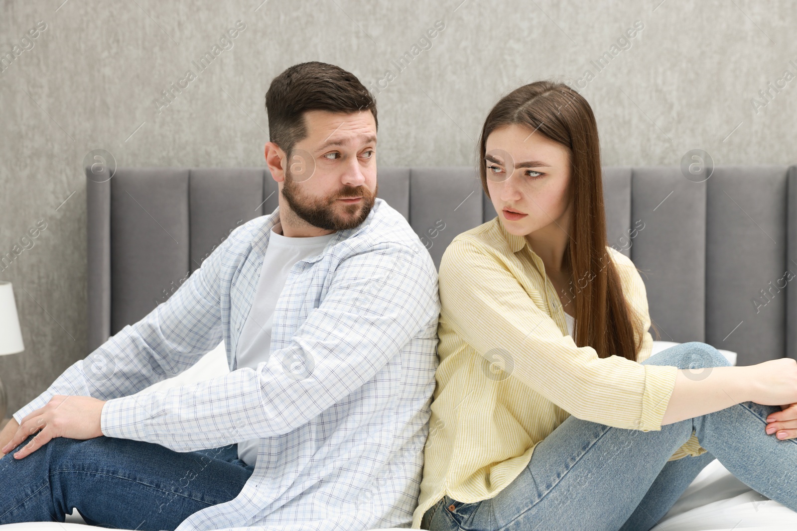 Photo of Resentful couple sitting on bed at home. Relationship problem