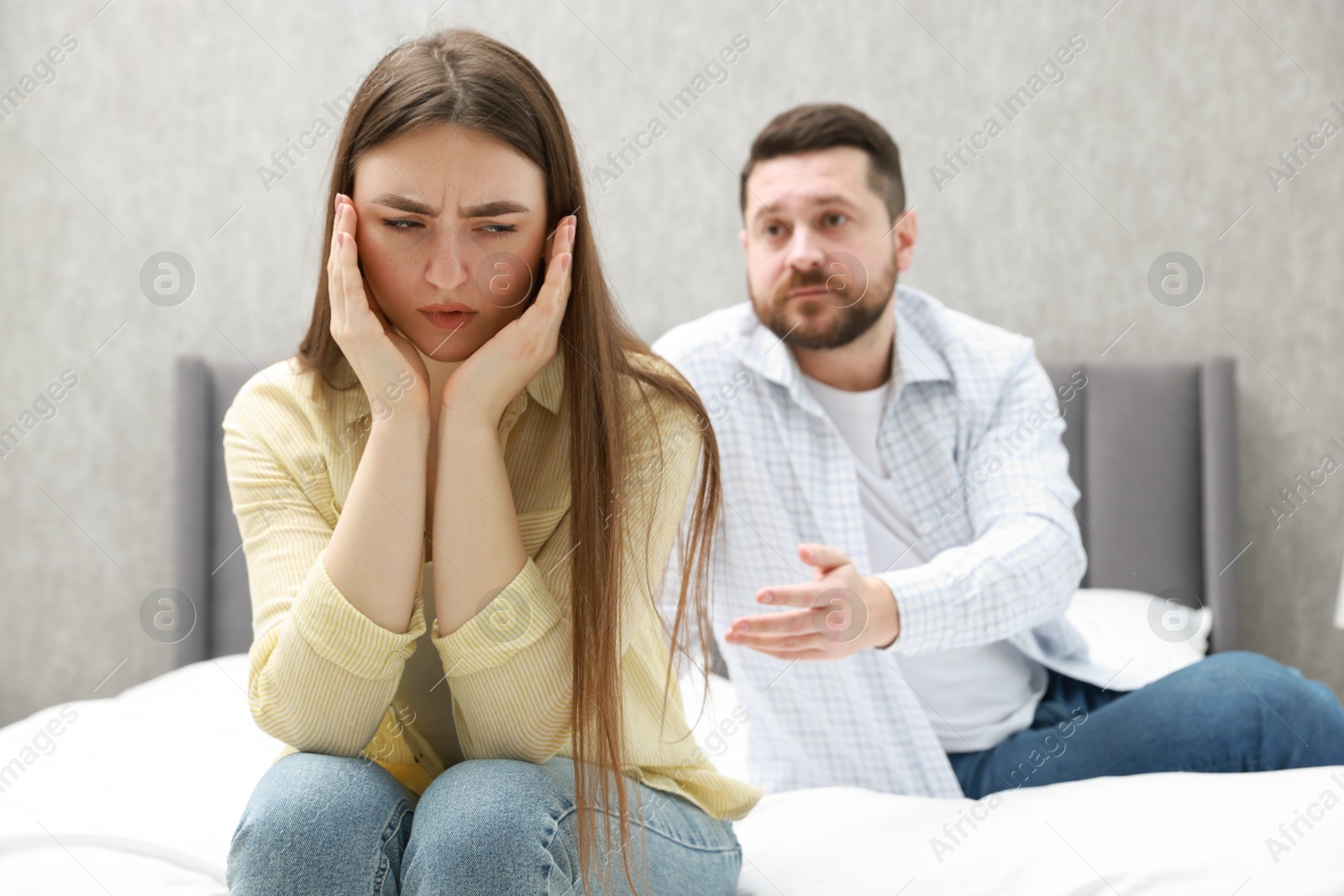 Photo of Resentful couple arguing on bed at home, selective focus