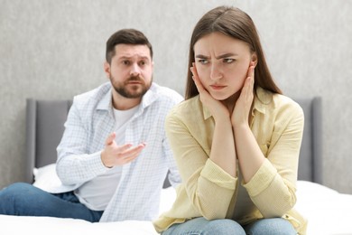 Photo of Resentful couple arguing on bed at home, selective focus