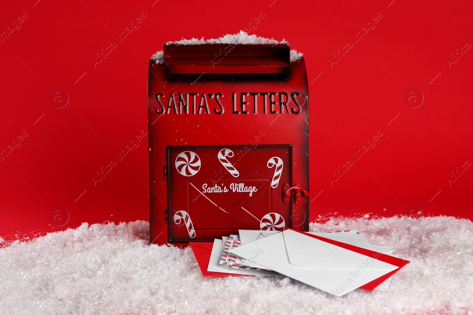 Photo of Santa Claus mailbox with letters on artificial snow against red background. Christmas tradition