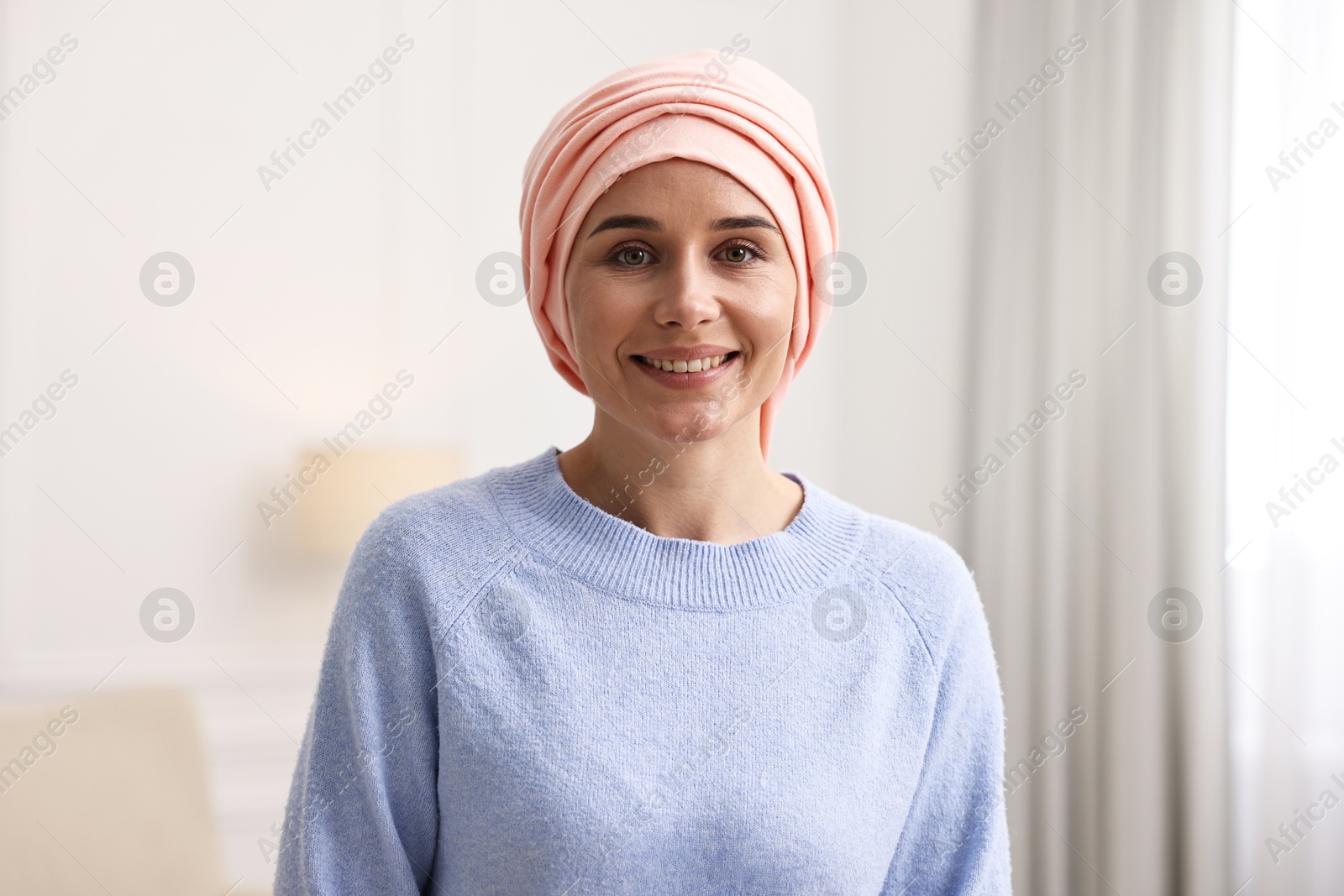 Photo of Portrait of smiling woman with cancer in headscarf indoors