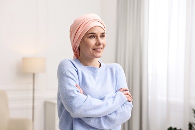 Portrait of smiling woman with cancer in headscarf indoors