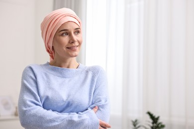 Photo of Portrait of smiling woman with cancer in headscarf indoors. Space for text