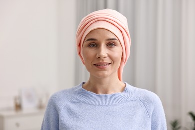 Photo of Portrait of smiling woman with cancer in headscarf indoors