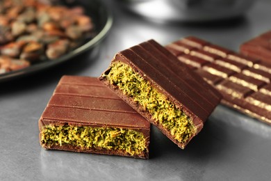 Photo of Pieces of tasty Dubai chocolate with pistachios and knafeh on grey table, closeup