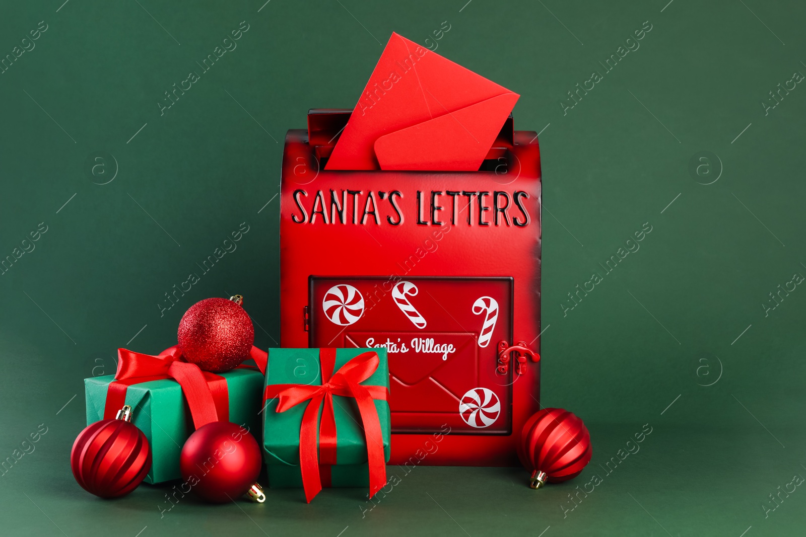 Photo of Santa Claus mail box with letter, gifts and Christmas baubles on dark green background