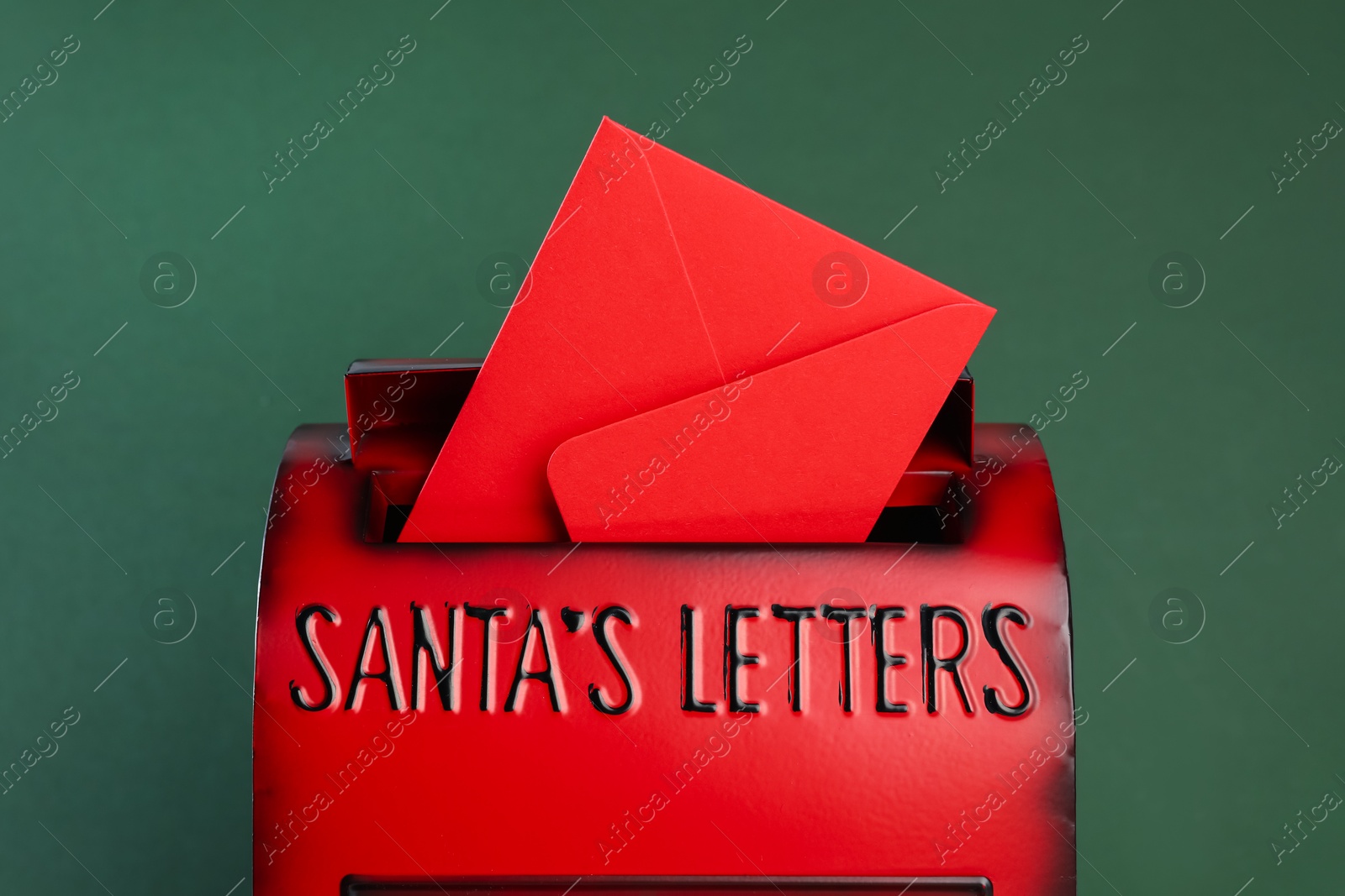 Photo of Santa Claus mail box with letter on dark green background, closeup. Christmas tradition