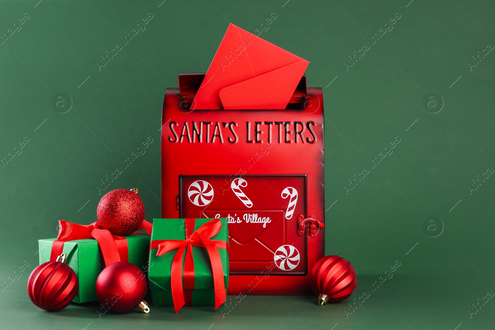 Photo of Santa Claus mail box with letter, gifts and Christmas baubles on dark green background