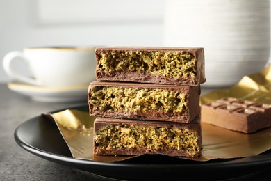 Photo of Pieces of delicious Dubai chocolate with pistachios and knafeh on grey table, closeup