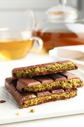 Photo of Pieces of delicious Dubai chocolate with pistachios and knafeh on white table, closeup